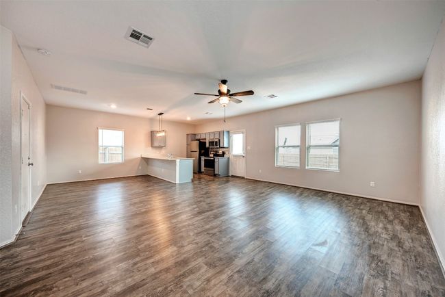Unfurnished living room with dark wood-type flooring, a ceiling fan, and baseboards | Image 6