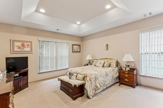 Bedroom with baseboards, visible vents, light colored carpet, and a raised ceiling | Image 15
