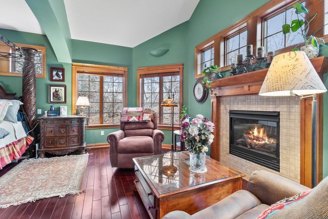 Primary bedroom sitting area with view towards woods, fireplace, extra high ceilings, mahogany hardwood floors. | Image 23
