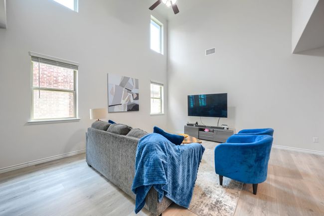 Living room featuring a towering ceiling, ceiling fan, wood finished floors, and baseboards | Image 6