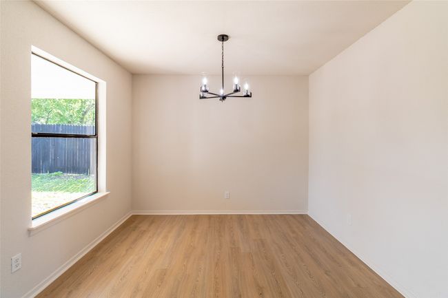 Spare room with light wood-style flooring, baseboards, and an inviting chandelier | Image 21