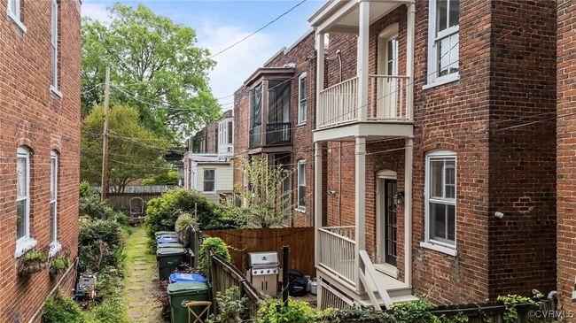 View of property exterior featuring brick siding, a balcony, and fence | Image 38