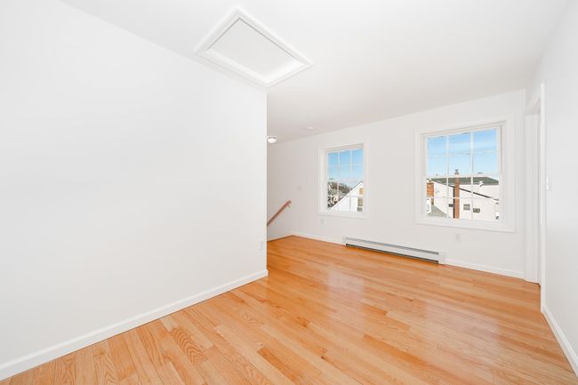 Unfurnished room with attic access, baseboards, light wood-style flooring, and a baseboard heating unit | Image 19