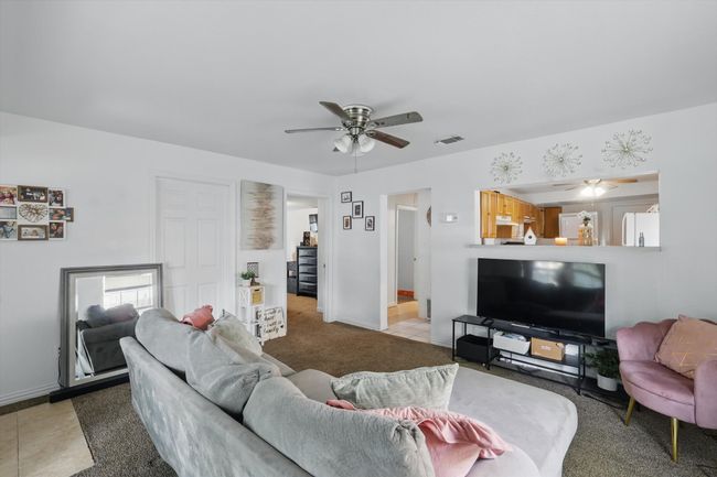 Carpeted living room with visible vents, baseboards, and ceiling fan | Image 5
