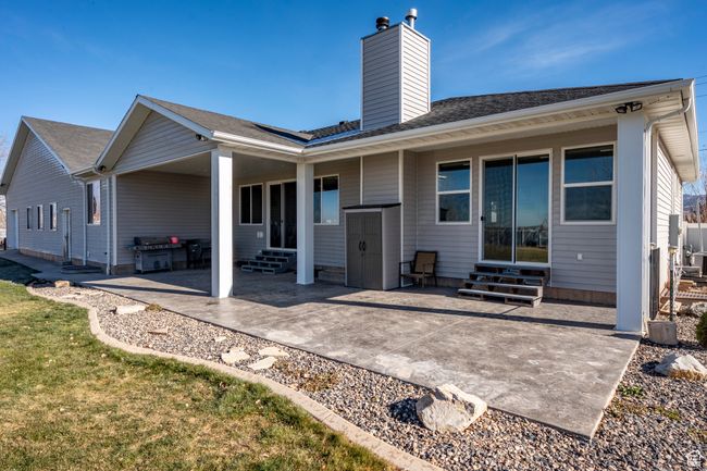 Rear view of property featuring a patio, entry steps, a chimney, and a shingled roof | Image 50