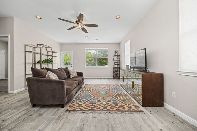 Living room featuring a ceiling fan, wood finished floors, and baseboards | Image 4