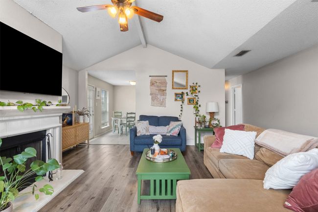Living room with ceiling fan, wood finished floors, a fireplace with raised hearth, and a textured ceiling | Image 8