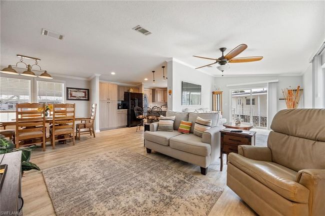 Living room with ornamental molding, light wood finished floors, visible vents, and ceiling fan | Image 15