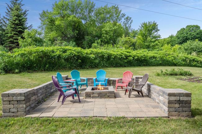 The large, private, wood-burning fire pit extends the outdoor entertaining space of this property. | Image 25