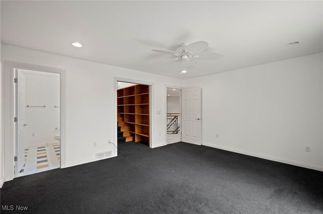 Unfurnished bedroom with dark carpet, recessed lighting, a spacious closet, a ceiling fan, and connected bathroom | Image 23