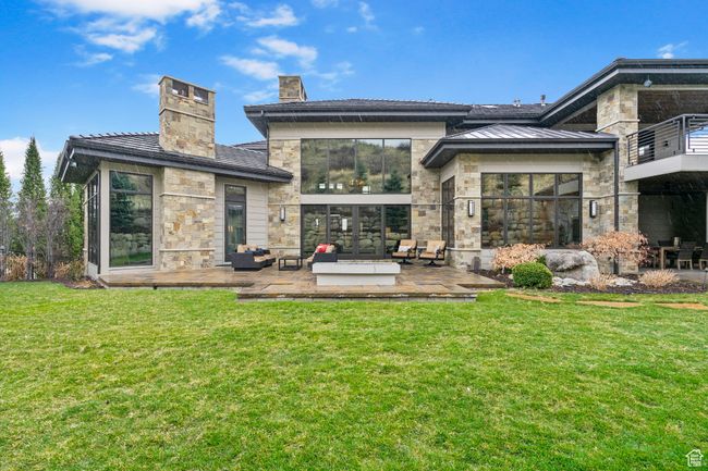 Rear view of house with a yard, a patio area, stone siding, and a chimney | Image 97