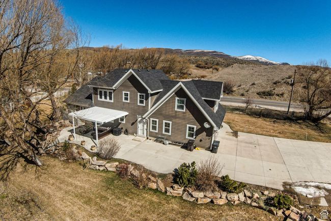Rear view of house featuring a lawn, a shingled roof, a mountain view, and a patio area | Image 46