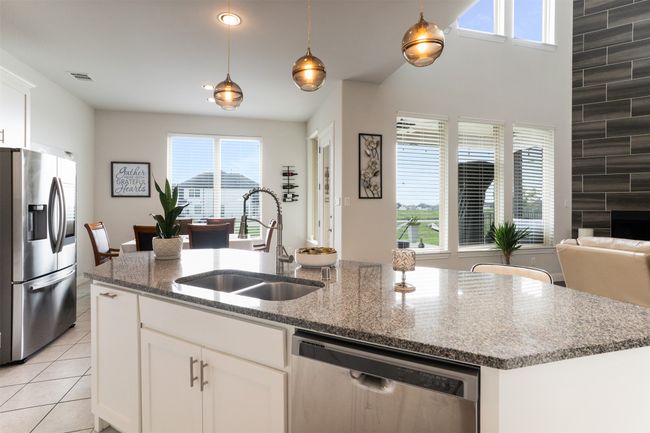 Kitchen featuring a sink, a kitchen island with sink, appliances with stainless steel finishes, light stone countertops, and visible vents | Image 13