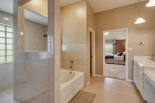 Bathroom featuring a bath, vanity, walk in shower, tile patterned flooring, and ensuite bath | Image 11