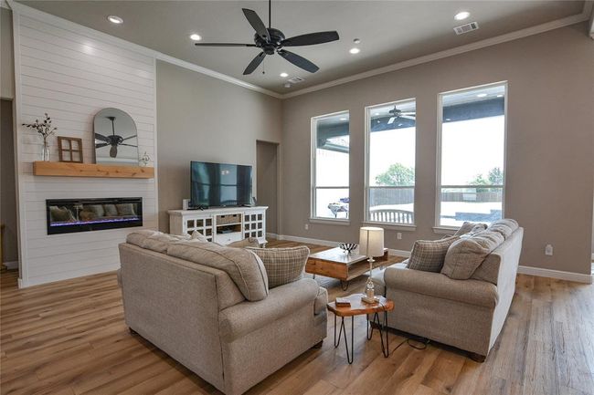 Living room featuring wood-style floors, ceiling fan, a fireplace, and crown molding | Image 16