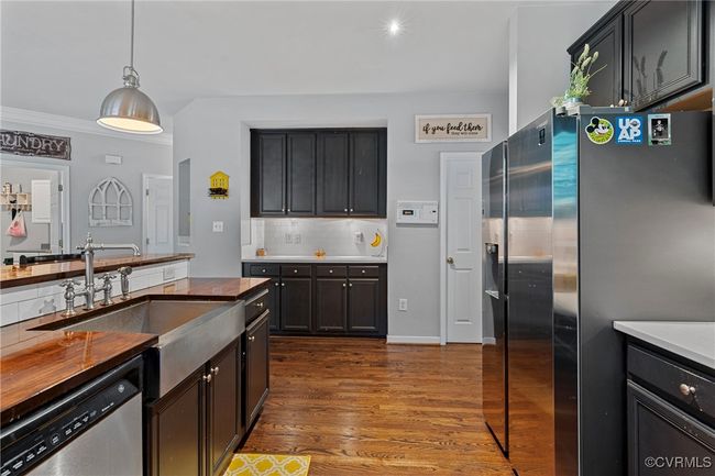 Kitchen with tasteful backsplash, stainless steel appliances, decorative light fixtures, a sink, and dark wood-style floors | Image 8