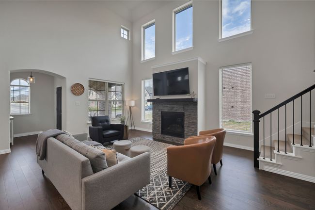 Living room featuring a stone fireplace, dark wood-type flooring, and a wealth of natural light | Image 6