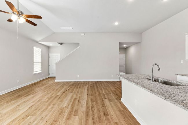Unfurnished living room with baseboards, visible vents, lofted ceiling, light wood-style floors, and a sink | Image 15