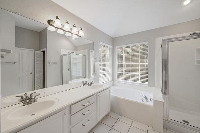Primary Full bathroom featuring separate stall shower, double vanity, a garden tub, vaulted ceiling, and tile flooring | Image 8