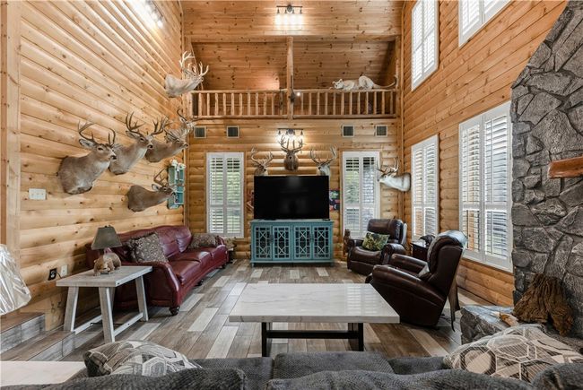 Living area with a high ceiling, wook-look tile floors, log walls, and healthy amount of natural light | Image 8