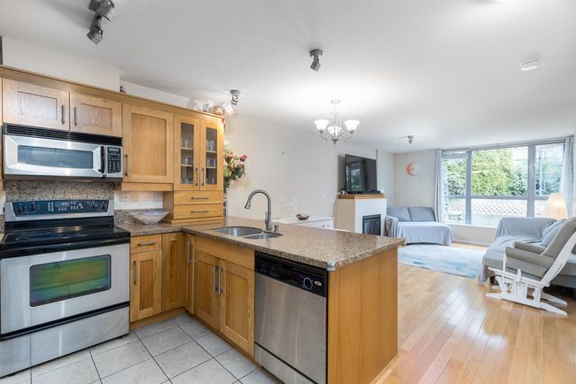 Kitchen featuring a peninsula, a sink, open floor plan, an inviting chandelier, and appliances with stainless steel finishes | Image 8