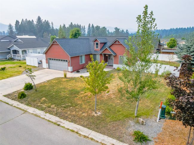 View of front of home featuring a garage, fence, concrete driveway, a front lawn, and roof with shingles | Image 10