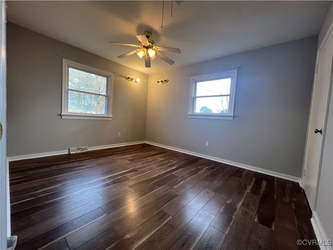 Spare room with dark wood-style floors, baseboards, visible vents, and a ceiling fan | Image 8