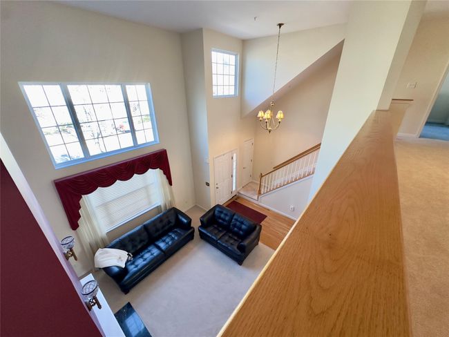 View from Loft showing Living area with baseboards, a towering ceiling, stairway, carpet flooring, and a chandelier | Image 11