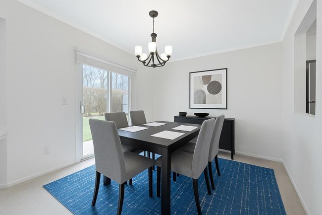 Carpeted dining room with an inviting chandelier and baseboards | Image 4