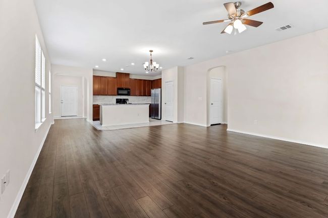 Unfurnished living room with a chandelier, dark wood-type flooring, a ceiling fan, arched walkways, and recessed lighting | Image 12