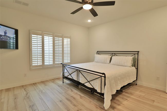 Bedroom with baseboards, a ceiling fan, visible vents, and light wood-style floors | Image 12