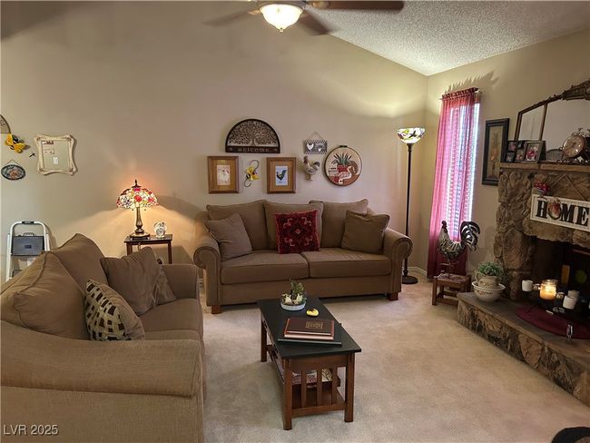 Living area with a ceiling fan, lofted ceiling, light colored carpet, and a textured ceiling | Image 7