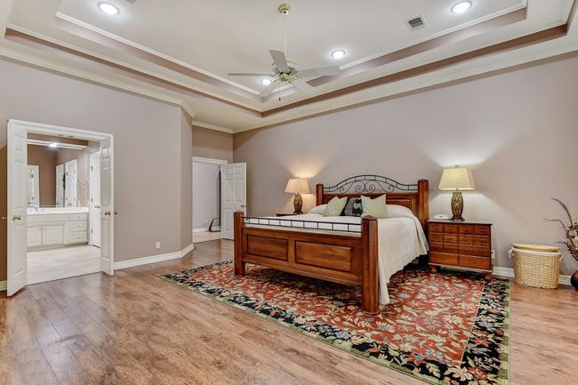 Bedroom featuring ornamental molding, wood finished floors, visible vents, and a raised ceiling | Image 15