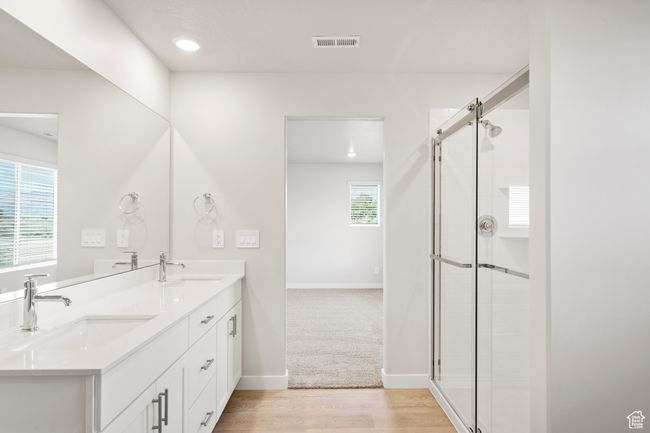 Bathroom featuring double vanity, a tile shower, wood finished floors, baseboards, and recessed lighting | Image 34