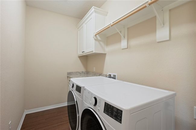 Washroom with cabinet space, independent washer and dryer, and dark wood finished floors | Image 9