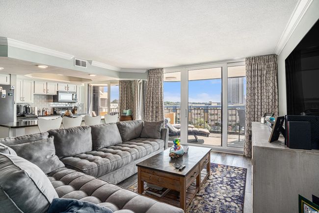 Living room with a textured ceiling, crown molding, and wood finished floors | Image 7
