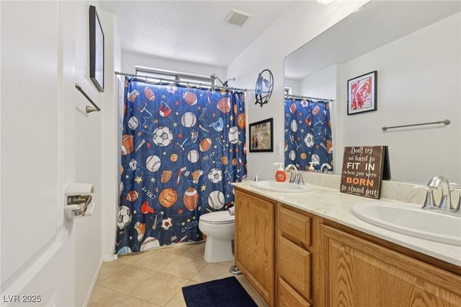 Bathroom featuring tile patterned floors, toilet, double vanity, and curtained shower | Image 38