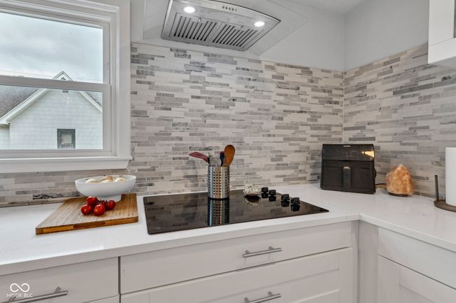 kitchen featuring decorative backsplash, exhaust hood, and light countertops | Image 15