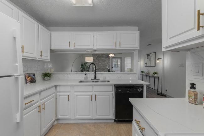 Kitchen featuring freestanding refrigerator, dishwasher, white cabinetry, and a sink | Image 23