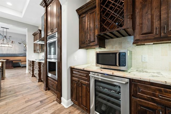 Beyond the kitchen on the way to the pantry is a wine fridge and microwave in the bar area. | Image 19