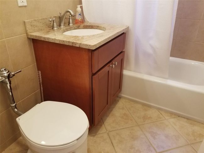 Full bathroom with shower / tub combo with curtain, vanity, tile patterned flooring, and tile walls | Image 8