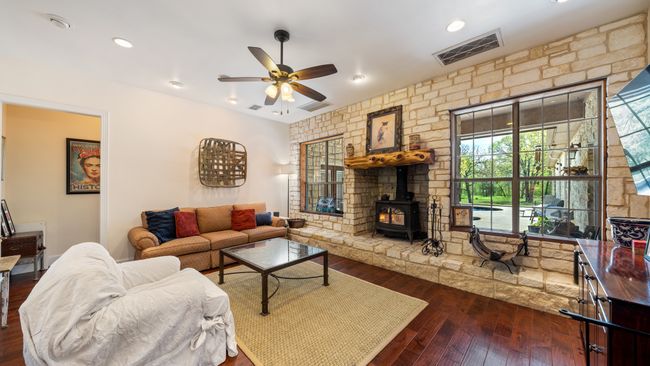 Living area with visible vents, ceiling fan, recessed lighting, dark wood finished floors, and a wood stove | Image 5