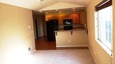 Kitchen with kitchen peninsula, black appliances, dark colored carpet, a breakfast bar area, and vaulted ceiling | Image 2