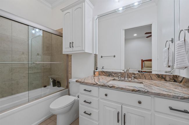 Full bathroom featuring vanity, combined bath / shower with glass door, crown molding, connected bathroom, and tile patterned flooring | Image 12