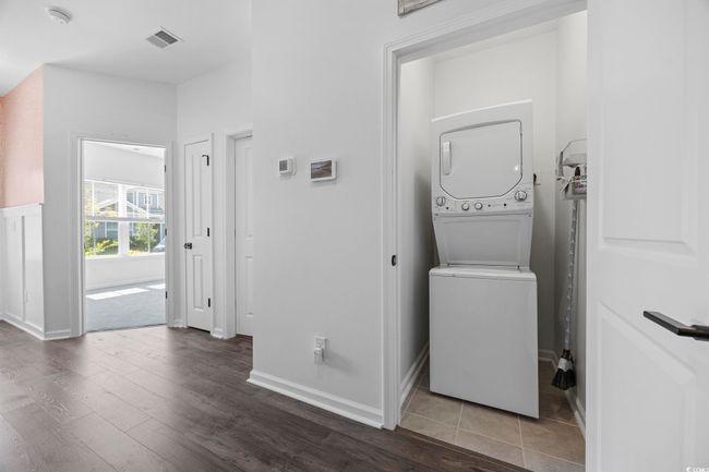 Laundry room featuring stacked washer and dryer, wood finished floors, laundry area, baseboards, and visible vents | Image 25