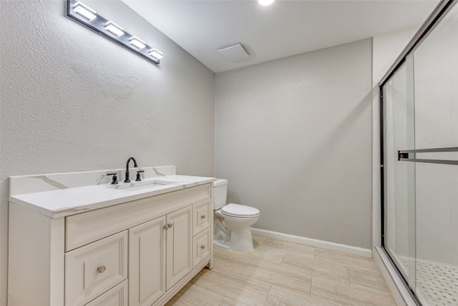 Bathroom featuring a stall shower, vanity, and a textured wall | Image 20