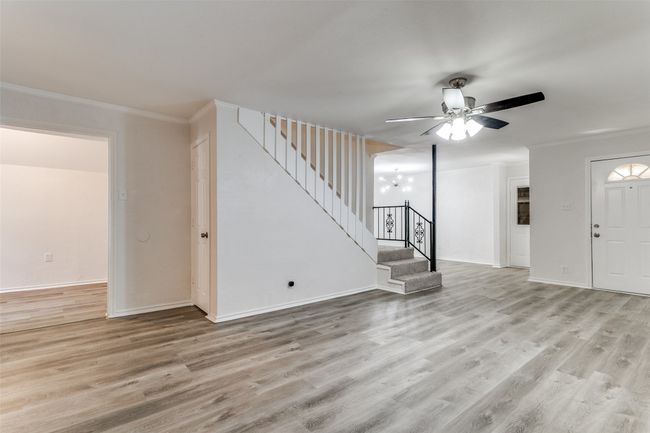 Foyer entrance featuring crown molding, stairs, light wood-style floors, ceiling fan, and baseboards | Image 7