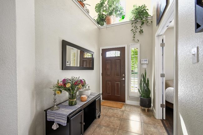 The bright and welcoming entrance foyer includes tile flooring and an office space with a French door entry. | Image 4