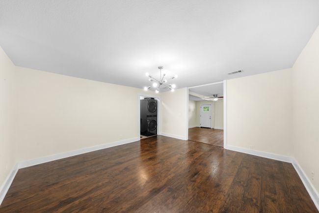 Unfurnished room featuring stacked washer / drying machine, a chandelier, dark wood-style flooring, ceiling fan, and baseboards | Image 7
