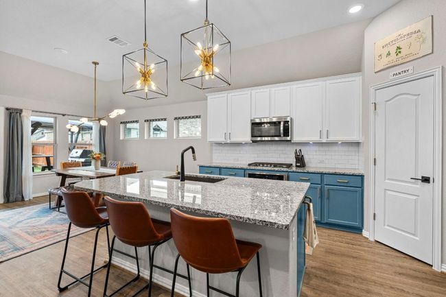 Kitchen with a sink, stainless steel microwave, a chandelier, high vaulted ceiling, and blue cabinetry | Image 14